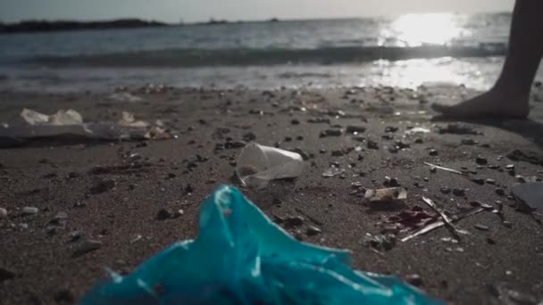 Close-up de homem mão pega lixo copo de plástico da praia de areia perto do mar Mediterrâneo na ilha de cyprus. Conceito de limpeza oceânica. Campanha para limpar. Poluição da água por resíduos plásticos e humanos — Vídeo de Stock