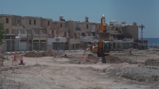 11 maj 2021 Cypern, Paphos. Byggmaskiner under vägreparationsarbeten på byggarbetsplats nära hamnen i Paphos stad. Anläggningsarbeten. Byggarbetsplats mot byggnader i centrum — Stockvideo