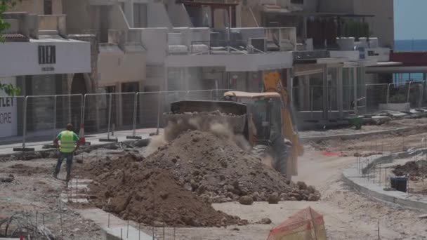 11 Mayıs 2021 Kıbrıs, Paphos. Paphos şehrinin limanı yakınlarındaki inşaat sahasında yol onarımı sırasında inşaat makineleri. Yol yapımı işe yarıyor. Şehir merkezindeki binalara karşı inşaat alanı — Stok video