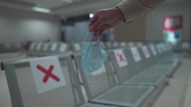 Onderwerp is quarantaine, nieuwe regels voor reizen per vliegtuig tijdens een coronavirus pandemie. Close-up van de man hand met medisch masker achtergrond van lege stoelen in terminal met sociale afstand markering — Stockvideo