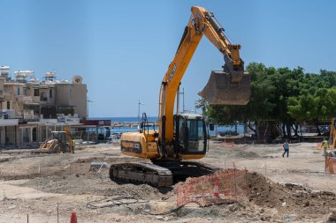 11 Mayıs 2021 Kıbrıs, Paphos. Ağır makineler ve inşaat ekipmanları Paphos şehir merkezindeki liman yakınlarındaki kaldırımların yenilenmesi üzerinde çalışıyor. Yol tamiri konsepti. İnşaat alanında kepçe doldurucu