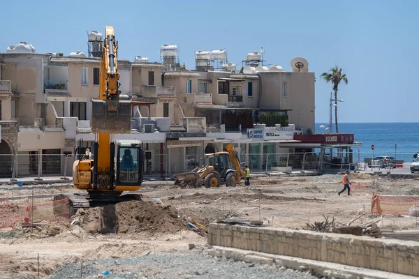 11 Mayıs 2021 Kıbrıs, Paphos. Paphos şehrinin limanı yakınlarındaki inşaat sahasında yol onarımı sırasında inşaat makineleri. Yol yapımı işe yarıyor. Şehir merkezindeki binalara karşı inşaat alanı — Stok fotoğraf