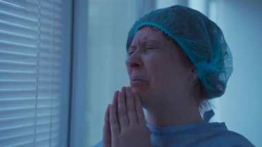 Ameliyattan önce hastanede ağlayan ve dua eden yüzü yaralanmış stresli bir kadın. Klinikteki eli kelepçeli endişeli hasta Tanrı 'dan yardım diliyor. Kazadan sonra korkan ve ambulansta dua eden kişi
