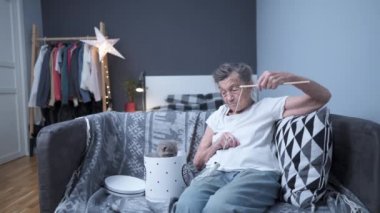 Kafkasyalı çok eski bir kadın evdeki kanepede kedi oyuncağıyla oynarken eğleniyor. Kıdemli kadın, arkadaşı İskoç heteroseksüel kedisiyle vakit geçiriyor. Kedi terapisi