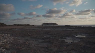 Agios Georgios Kıbrıs 'ın Rocky kıyısında. Yeronisos adasının manzarası. Kıbrıs 'ın Paphos kentindeki Agios Georgios Pegeias limanında gün batımı. Akamas Yarımadası ve Geronisos Adası