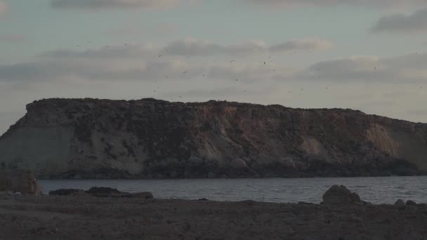 Rotsachtige kust van Agios Georgios Cyprus. Uitzicht op het eiland Yeronisos. Zonsondergang bij Agios Georgios Pegeias haven in Paphos, Cyprus. Het schiereiland Akamas en het eiland Geronisos — Stockvideo