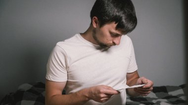 İlaçlı adam ilacın tıbbi kullanım talimatlarını okur. Erkek, evde yatakta oturan hapların talimatlarını okur. Reçete ve ilaç tedavisi, yan etkiler kavramı.