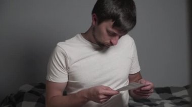 Akşam yemeğinden önce ya da sonra yatak odasında yatakta oturan bir adam bunu kontrol etmek için ilaç etiketi okuyor. Konsantre erkek eğitim ilaçlarını gözden geçiriyor. İlaç almadan önce broşür okuyan adam.