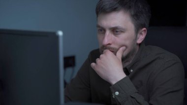 Genç beyaz adam bilgisayar başında fazla mesai yapıyor ve ofisteki monitörden dolayı göz yorgunluğu çekiyor. Erkek, bilgisayar üzerinde çalışırken stresli zaman geçiriyor. Yorgun programcı stresli iş, iş yerinde stres.