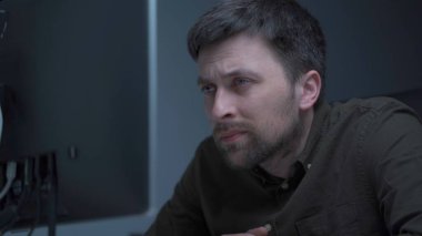 Genç beyaz adam bilgisayar başında fazla mesai yapıyor ve ofisteki monitörden dolayı göz yorgunluğu çekiyor. Erkek, bilgisayar üzerinde çalışırken stresli zaman geçiriyor. Yorgun programcı stresli iş, iş yerinde stres.