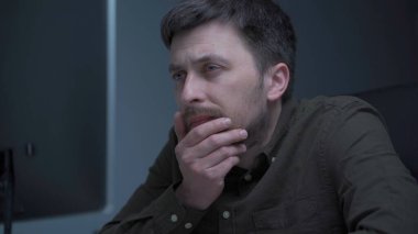 Bilgisayarda çalışan yorgun bir erkek. Ofiste yorgun ve üzgün bir adam. Stresli iş, iş yerinde stres. Yazılım geliştiricisi projenin fazla mesaisi sırasında çok yorgun görünüyor, bilgisayar üzerinde çalışıyor.