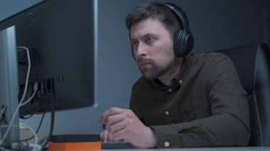 Genç beyaz adam bilgisayar başında fazla mesai yapıyor ve ofisteki monitörden dolayı göz yorgunluğu çekiyor. Erkek, bilgisayar üzerinde çalışırken stresli zaman geçiriyor. Yorgun programcı stresli iş, iş yerinde stres.