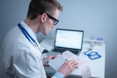 Kalp hastalıklarına zamanında bakmanın konusu. Kalp hastalığı miyokardiyal enfarktüs. Hastane ofisindeki masada elektrokardiyogramı analiz eden doktor. Klinikte kardiyolog. Doktor EKG 'ye bak..