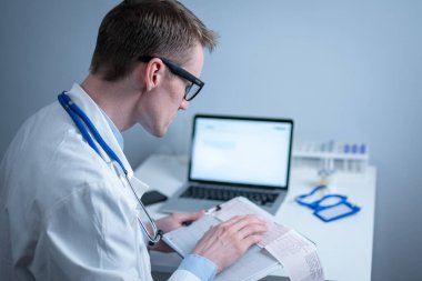 Kalp hastalıklarına zamanında bakmanın konusu. Kalp hastalığı miyokardiyal enfarktüs. Hastane ofisindeki masada elektrokardiyogramı analiz eden doktor. Klinikte kardiyolog. Doktor EKG 'ye bak..