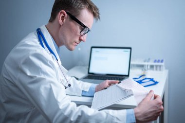 Kalp hastalıklarına zamanında bakmanın konusu. Kalp hastalığı miyokardiyal enfarktüs. Hastane ofisindeki masada elektrokardiyogramı analiz eden doktor. Klinikte kardiyolog. Doktor EKG 'ye bak..