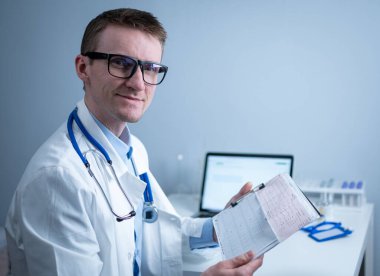 Kalp hastalıklarına zamanında bakmanın konusu. Kalp hastalığı miyokardiyal enfarktüs. Hastane ofisindeki masada elektrokardiyogramı analiz eden doktor. Klinikte kardiyolog. Doktor EKG 'ye bak..