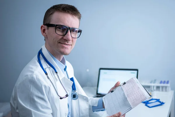 Cardiologist reading an ECG print-out. Doctor analyzing electrocardiogram. Practitioner examine patient test results. Medical and healthcare concept. Physician looking at cardiogram at medical office.