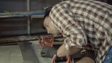 Ski technician is working on fixing and preparing for the season pair of downhill skis at his ski shop. Ski tuning and repair. Mechanic repairing ski in workshop. Winter shop worker doing base repair