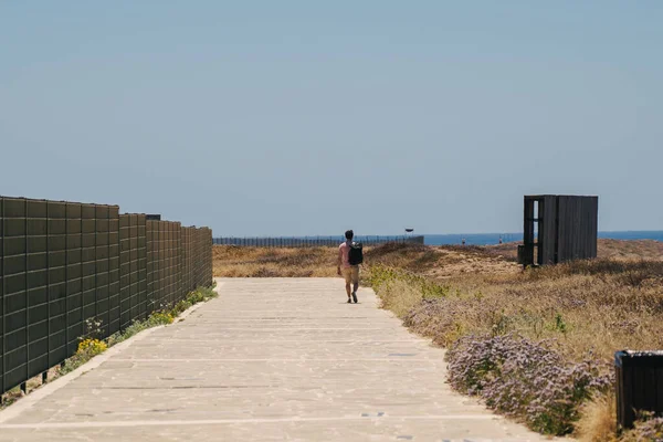 Tema de explorar la isla de Chipre a pie. El hombre con una mochila es paseos a lo largo del mar por la calzada costera en la ciudad de Paphos en Chipre en verano. Caminata con vistas al mar Mediterráneo —  Fotos de Stock