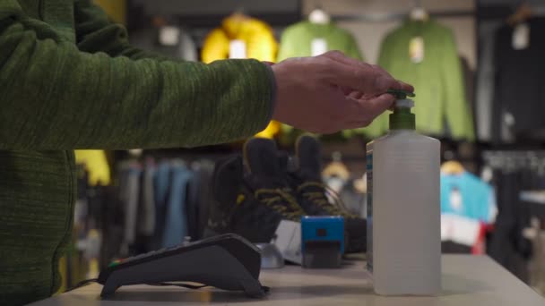 세일즈맨 이 스포츠 용품 점의 밀봉 뒤에서 손 소독용 알코올 젤을 판매하고 있습니다. 스캐너는 일을 시작하기 전에 양손을 씻는다. 전염병 이 창궐하는 동안 사업에 대한 새로운 규칙을 만들었습니다. 새로운 정상 — 비디오