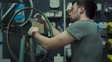 Professional bicycle mechanic adjusting one spoke at time special tool for tensioning spokes. Mountain bicycle repairing. Master fixing wheel spokes working in bike repair shop. Wheel installation