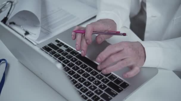 En kvinnlig doktor som jobbar på laptop och skriver på tangentbordet på kliniken. Telemedicin, telekonferens. Online chatt. Sjukvård och medicinskt ämne. Kvinnlig läkare konsultation på nätet, skriva rapport — Stockvideo