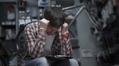 Individual entrepreneur analyzes costs bicycle shop. Concept small business owner bankruptcy, financial problems and crisis, money overspend. Business is going down. Depressed male checking finance