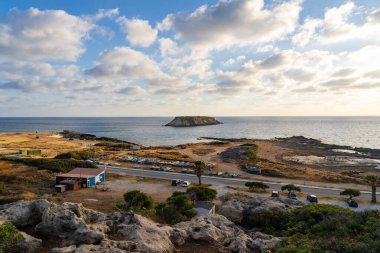 Agios Georgios Kıbrıs 'ın Rocky kıyısında. Yeronisos adasının manzarası. Kıbrıs 'ın Paphos kentindeki Agios Georgios Pegeias limanında gün batımı. Akamas Yarımadası ve Geronisos Adası.
