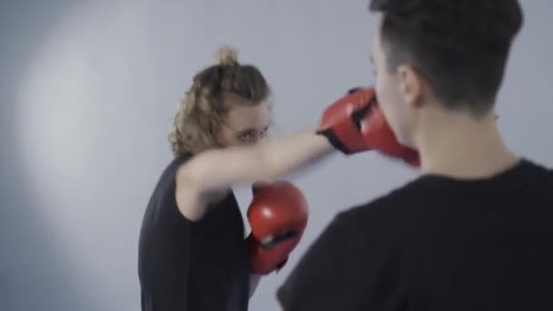 Tema femminile di arte marziale. Sportiva in guanti sportivi rossi che pratica pugni sulle zampe tenuti da personal Tekwando trainer in palestra. Esercizi di kickboxing e punzonatura con pad di calcio in mano allenatore — Video Stock