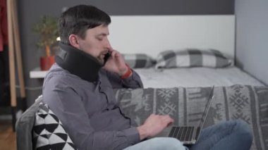 Dizüstü bilgisayarın arkasında çalışırken kazara çalışan bir adam ve telefonda boyun ağrısından nasıl kurtulacağına dair tavsiye almak için doktoru arıyor. Protez için boyun desteği. Boyun omurunda kırık var.