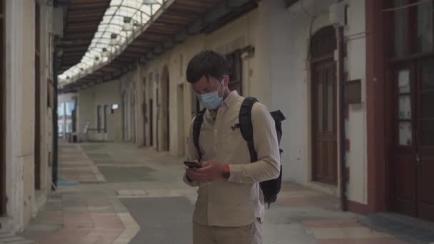 Maskované mužské turistické procházky na uzavřeném trhu během pandemie koronaviru, uzamčení Kypru. Muž v masce prochází obchodem v centru města. Žádní turisté, bankrot malých podniků pod COVID 19 — Stock video