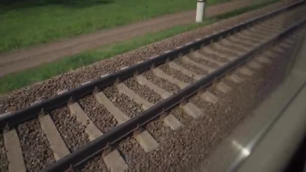 Vista na linha férrea a partir da janela do trem. O comboio da bala anda na linha férrea. Caminhos de comboio. Viagem de trem conceitual. Trilhos móveis e dormentes. Transportes, viagens, estradas, caminhos-de-ferro — Vídeo de Stock