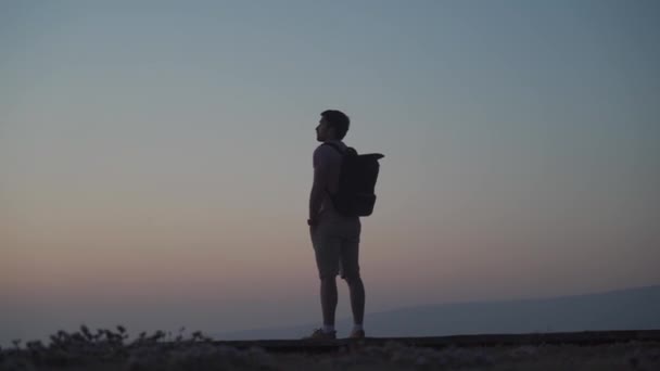 Człowiek podróżnik z plecakiem podziwia widok na zachód słońca i Morze Śródziemne z drewnianego molo na wyspie Cypru. Koncepcja wolności. Wędrówki, mężczyzna cieszący się zachodem słońca, samotny podróżnik — Wideo stockowe