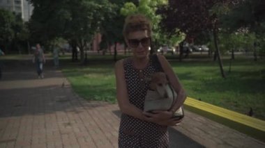 Hayvanlarla arkadaşlık, kıdemli kadın sahibi şehirde evcil hayvan çantasıyla gezer. Küçük köpekler için taşınabilir çanta ve yazın yürüyüşe çıkan yaşlı bir bayan.