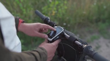 Motorlu bilgisayar navigatörü. Modern teknoloji. Küresel konumlandırma sistemi olan bisiklet gidonu. Bisikletçi yolculuk sırasında bisiklet bilgisayarını kontrol ediyor. GPS aygıtı üzerinde rota planlaması ve çevrimdışı haritaları görüntüleme