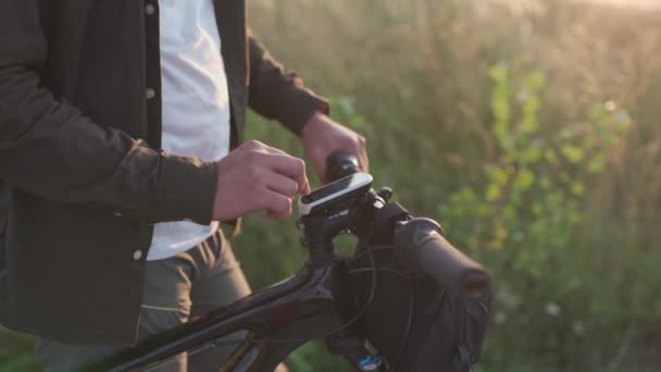 İnsanlar, spor, aktif yaşam tarzı konsepti. Navigator aygıtı kullanan bisikletçi haritayı inceler ve dışarıda bisiklet sürerken ekranda GPS koordinatlarına bakar. Bisiklet gidonundaki etkinlik izleyici — Stok video