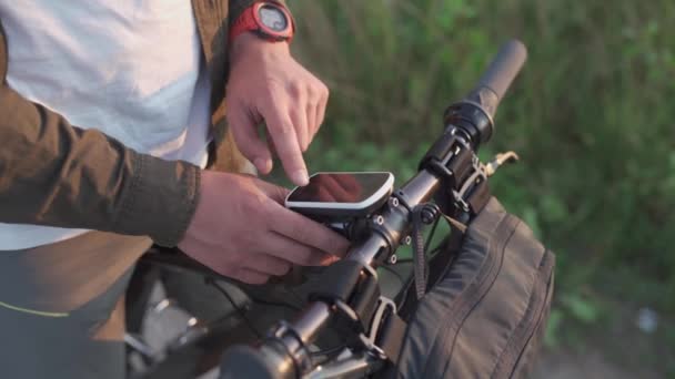 Ποδηλάτης χρήση ποδήλατο υπολογιστή στο τιμόνι του ποδηλάτου βουνού στη φύση. Ταξιδιώτης σε κύκλο κοιτάζει στο χάρτη, χτίζει διαδρομή χρησιμοποιώντας GPS σε πλοήγηση ποδήλατο. Δραστηριότητα tracker και offline χάρτες για βόλτες με ποδήλατο — Αρχείο Βίντεο