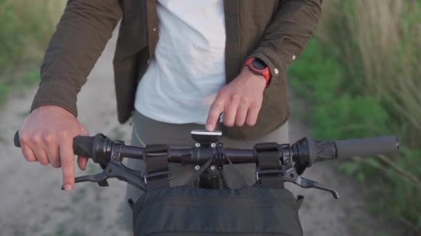 Люди, спорт, концепція активного способу життя. Велосипедист за допомогою навігатора вивчає карту і шукає координати GPS на екрані гаджета під час їзди на відкритому повітрі. Трекер активності на кермі циклу — стокове відео