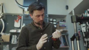 Bisiklet tamiri ve servis atölyesinde bisiklet çatalını tamir eden adam. Bisiklet tamircisi motorun ön şok emicisini tamir ediyor. Meslek teması. Teknisyenler bisiklet parçalarını tamir ediyorlar.