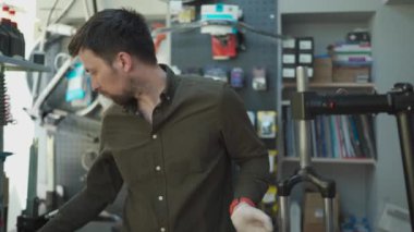 Bisiklet tamiri ve servis atölyesinde bisiklet çatalını tamir eden adam. Bisiklet tamircisi motorun ön şok emicisini tamir ediyor. Meslek teması. Teknisyenler bisiklet parçalarını tamir ediyorlar.