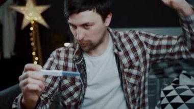 Bebeğin hamilelik testinin pozitif çıkmasını bekleyen mutlu bir adam mutluluğu engelleyemez. Heyecanlı erkek hamilelik testine bakıyor ve çok memnun. Bu her zaman istediği şeydi. Babamda hamilelik testi var.