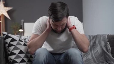 Boynunda boyunluğu olan engelli bir adam doktorla telefonda konuşuyor, evdeki oturma odasında kanepede otururken acı çekiyor. Servikal korse kullanan yaralı genç adam cep telefonuyla arama yapıyor.
