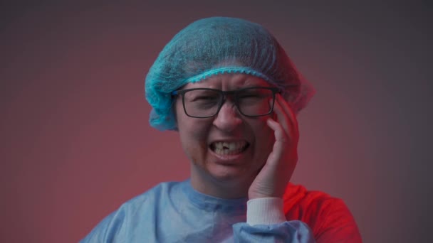 Retrato de una paciente en el hospital con ropa médica después de un accidente de coche recibió lesiones en la cara y dental, mirando a la cámara en el fondo gris. Llorando mujer víctima de violencia doméstica y abuso — Vídeos de Stock