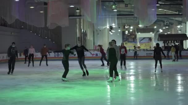 ウクライナ、キエフ2020年12月20日ショッピングセンターの夢の町でスケートリンク。マスクの人々のグループは、陰湿な隔離中に屋内アイスリンクでスケート。コロナウイルスの氷のアリーナで多くの覆面の訪問者 — ストック動画