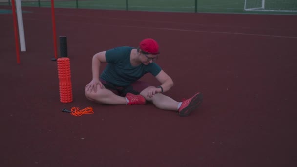 Fat woman doing warm-up, stretching muscles after jumping rope training at stadium. Plump woman relaxes muscles after workout with foam roller on street gym. Topic of losing weight, losing weight — Stock Video