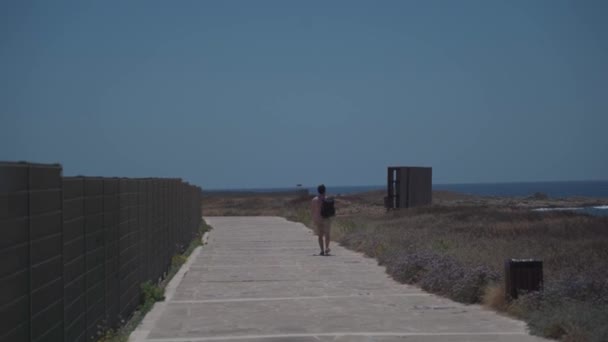 Broadwalk litoral ao longo do mar mediterranean no console do cyprus na cidade de paphos. Viajante com mochila caminha ao longo do caminho perto da beira-mar. Pessoas activas. Viagens, caminhadas e estilo de vida ativo — Vídeo de Stock