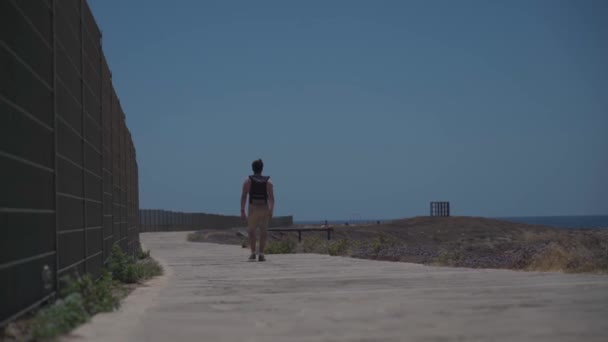 Homem turista com mochila passeio ao longo do caminho a pé na costa rochosa do Mar Mediterrâneo na cidade Paphos de Chipre no verão tempo quente ensolarado. Banda larga costeira. Explore a ilha de Chipre a pé. Caminhadas — Vídeo de Stock