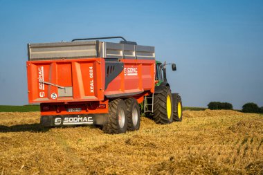 25 Ağustos 2021 'de Fransa' nın Brittany bölgesinde güneşli bir yaz gününde New Holland 'da. Sarı hasat tahıl tarlasında birleşiyor. Yaz hasadı. Tahıl tarlasında hasat. Yeni Hollanda Tarım.