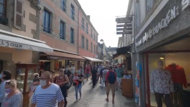 사람들은 프랑스 브르타뉴 지역에 있는 식당 과상 점들을 가지고 옛 도시 콩 카 니우를 지나고 있다. 프랑스, 브레 뉴 콘 카르 네 우 (Bretagne Concarneau) 2021 년 8 월 31 일. 프랑스의 성벽으로 둘러싸인 중세 도시 콩 카 니우 — 비디오