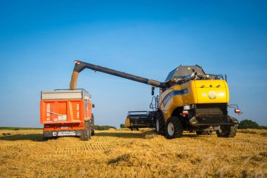 New Holland CX8080 güneşli bir yaz gününde Fransa, Brittany bölgesinde 25 Ağustos 2021. Sarı hasat tahıl tarlasında birleşiyor. Yaz hasadı. Tahıl tarlasında hasat. Yeni Hollanda Tarım.